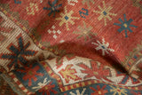 Textured pile of antique Kazak rug with geometric starbursts in madder root red and cream.