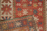 Close-up of antique Kazak rug's hand-knotted pile, terra cotta starbursts, and woven reverse.
