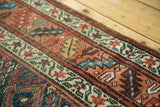Antique Kurdish Bijar rug border with geometric and stylized motifs in indigo, blush apricot, and ivory.