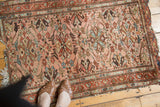 Vintage Lilihan rug with dust rose, terra cotta floral pattern and visible tattered ends.
