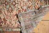 Hand-knotted foundation and tattered end of a vintage Lilihan rug with rose and blue tones.