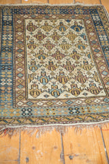 Vintage Caucasian rug corner detail showing geometric lattice motif, light tattered ends.