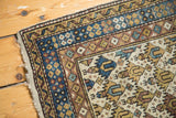 Close-up of vintage Caucasian rug corner, light blue, pale gold geometric border, lattice diamond motif.