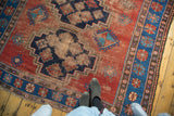 Vintage Caucasian rug: stepped diamond and gul motifs in indigo, terra cotta, with even wear.