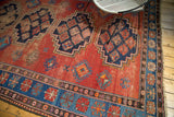 Vintage Caucasian carpet's terra cotta field, indigo stepped medallion, and patterned border.