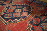 Terra cotta, indigo geometric stepped patterns on vintage Caucasian rug, showing mostly visible knot heads.