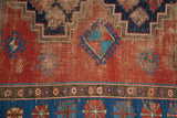 Primitive gul and pinwheel motifs on terra cotta, indigo vintage Caucasian carpet with wear.