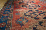 Vintage Caucasian rug detail, terra cotta field, indigo border, primitive geometric motifs, and visible wear.