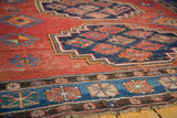 Worn terra cotta field and indigo geometric border on a vintage Caucasian carpet.