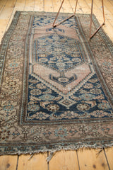 Worn end and tattered fringe of an antique Malayer rug, with dusty rose and blue.