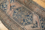 Close-up of antique Malayer rug, showing the worn blush and blue hexagonal medallion with floral motifs.