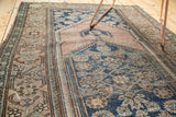 Worn edge detail of antique Malayer rug: dusty rose border with tatter, muted blue field.
