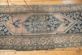 Antique Malayer rug's tattered edge with pale floral border and dark blue pattern.