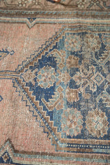 Close-up of antique Malayer rug pile, showing wear and dusty rose and muted blue Herati motifs.