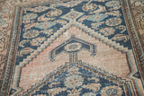 Antique Malayer rug's blush, navy, and light blue reciprocating spandrel motif with wear.