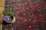 Intricate blue floral motifs on the vintage German Sarouk's hand-knotted cranberry red pile.