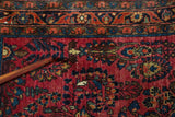 Close-up of vintage Sarouk rug's cranberry red field, floral vines, and scattered white knots.