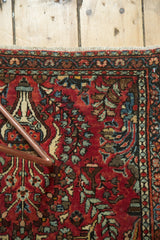 Hand-knotted vintage Sarouk runner's fringed end with cherry red field and intricate floral motifs.