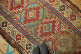 Antique Caucasian runner's primitive geometric gul panels in brick red, sky blue, and saffron with visible wear.