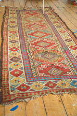 Tattered end of antique Caucasian rug, geometric panels in brick red, sky blue, saffron, aged green.