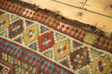 Antique Caucasian runner edge with tatter; brick red, sky blue, and saffron geometric patterns.