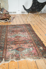 Hard tatter at end of vintage Mehriban rug, dusty magenta and teal geometric patterns.
