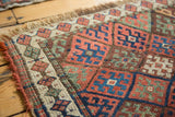 Corner of antique Jaff Kurd rug displaying geometric diamond lattice in madder red and indigo.