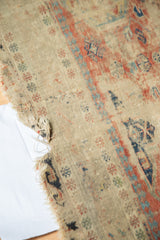 Tattered side and historic wear on an antique Caucasian Soumac rug, featuring faded red, blue geometrics.