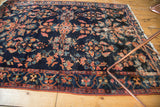Corner of vintage Lilihan rug, indigo blue field, floral blossoms, border, and fringe with wear.