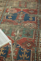 Hard tatter and holes on antique Caucasian rug revealing red, blue, and ivory geometric pattern.