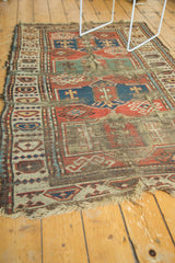 Tattered fringe, madder red and ivory geometric patterns on an antique Caucasian rug.