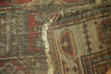 Antique Caucasian rug detail showing hard tatter, exposed hand-knotted foundation, and madder red palette.
