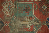 Hard tatter, holes, and exposed foundation detail of a red and green antique Caucasian rug.