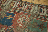Madder red, blue, and mallard green geometric motifs on a tattered antique Caucasian rug.