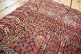 Antique Turkmen rug segment displays pale cochineal red geometric animal motifs, with visible wear.