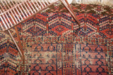 Geometric patterns in cochineal red and navy on antique Turkmen rug, with perimeter hole.