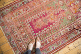 Antique Mudjur rug's tattered edge, worn magenta field, and pistachio geometric motifs.