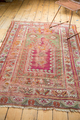Frayed corner of antique Mudjur prayer rug, with pistachio green and magenta patterns.