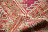 Tattered edge and exposed foundation on an antique Mudjur rug, featuring magenta and green motifs.