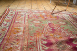 Storied magenta and pistachio geometric patterns with visible wear on an antique Mudjur rug.