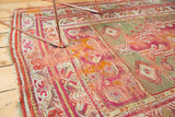 Worn fringe and exposed foundation on the antique Mudjur rug's colorful magenta and green borders.