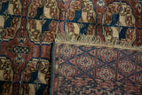 Hand-knotted Turkmen rug showing geometric back, fringed edge, and Bokhara gul pile.