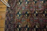 Close-up of vintage Turkmen Bokhara gul pattern in dark eggplant, navy, and ivory.