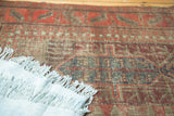 Antique Persian Belouch rug detail showcasing geometric patterns, indigo, blush red, and visible foundation.