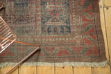 Corner detail of antique Belouch rug, showcasing indigo, red, wear revealing foundation, and fringe.