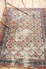 Antique Dagestan Caucasian rug's geometric lattice, floral motifs, and visible fragmentation.
