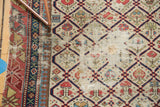 Antique Dagestan rug detail: ivory field, navy lattice, geometric motifs, and exposed foundation.