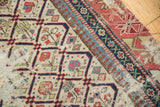 Fragmented antique Dagestan rug corner with ivory lattice, ruby flora, and geometric border.