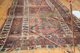 Vintage Caucasian runner showcasing madder red field, blooming motifs, and exposed foundation wear.