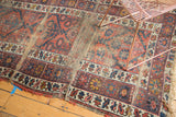 Tattered vintage Caucasian runner detail with exposed foundation, madder red, and navy geometric patterns.